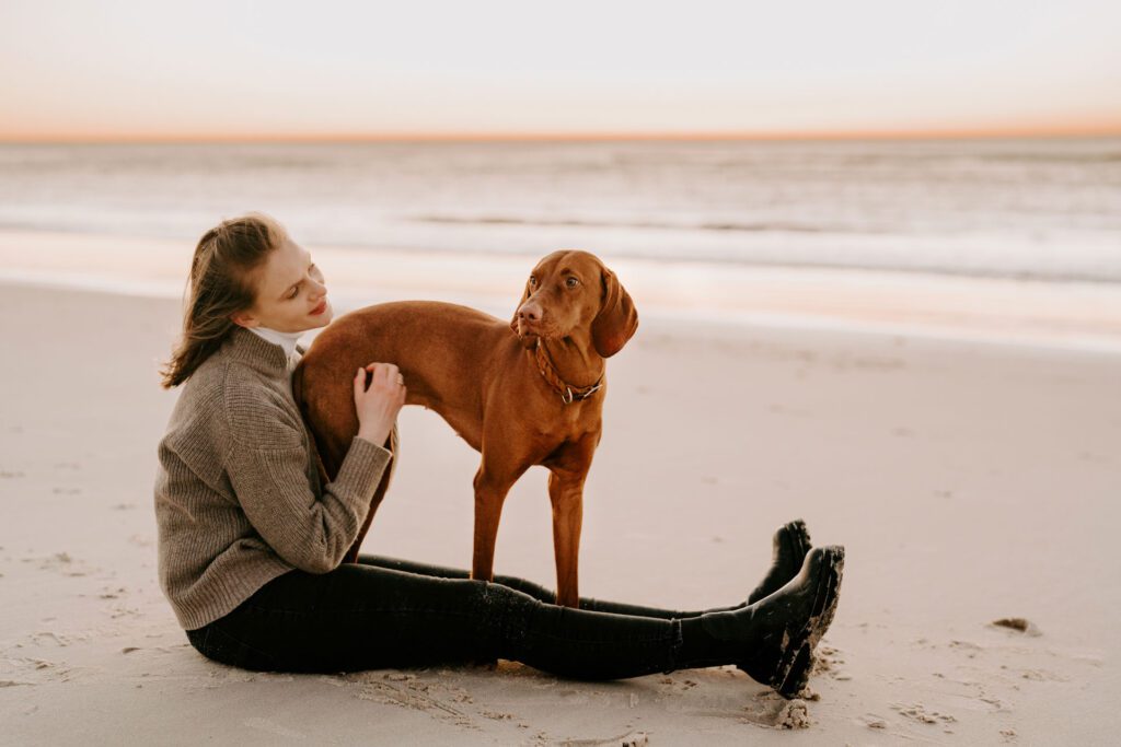 Junge Frau mit ihrem Magyar Vizsla am Strand von Sylt: Ein entspannter Moment eingefangen, während die junge Frau mit ihrem Magyar Vizsla die malerische Kulisse von Sylt am Strand genießt. Die natürliche Schönheit der Umgebung und die harmonische Verbindung zwischen Mensch und Hund stehen im Mittelpunkt dieses Bildes.